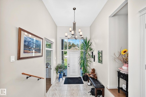 Spacious, bright entryway with tiled floor, a chandelier, and a large front window. - #7 53216 Rge Road 264, Rural Parkland County