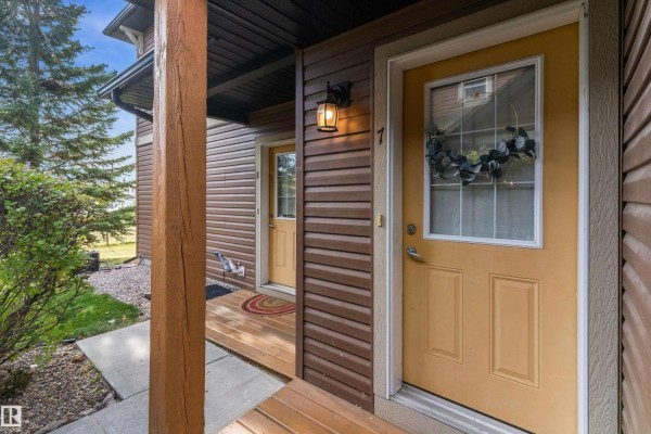Close-up of a yellow front door with a wreath, next to another door and porch. - #7 671 Silver Berry Rd Nw, Edmonton