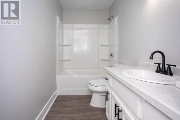 Bathroom with a white toilet, bathtub, vanity, and black fixtures. - #7 8 Glen Stewart Drive, Stratford