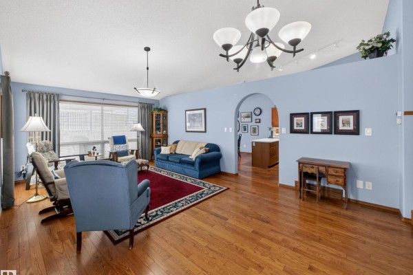 Living room with blue walls, hardwood floors, fireplace, sofa, and view into kitchen. - #7 85 Gervais Rd, St  Albert
