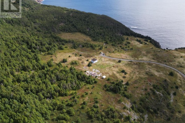 Aerial view of a property with a small house and debris, bordering a dense forest and the ocean. - 7 Amys Hole Road, Jobs Cove