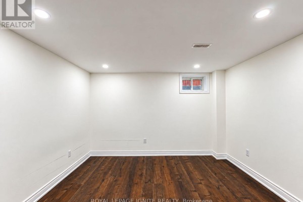 An empty unfinished basement room with white walls, wood floors, and recessed lighting. - 7 Aquilina Court, Ajax