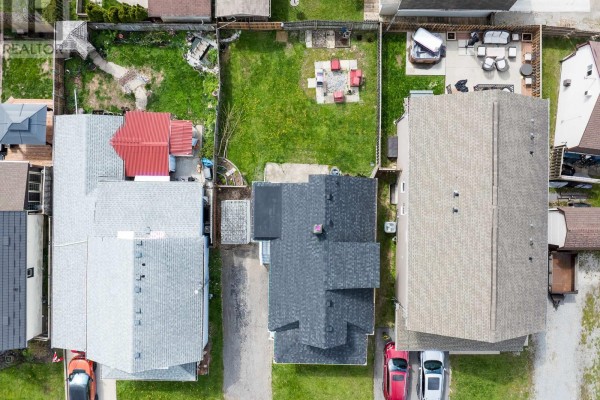 Aerial view of the property showing the house, driveway, fenced backyard with a fire pit, and neighboring houses. - 7 Battle Street, Thorold