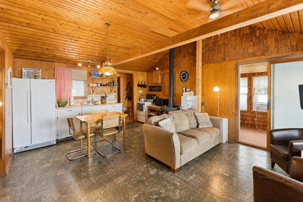 Living area with wood paneling, wood stove, sofa, and an open doorway to the kitchen. - 7 Block 4 Road, Betula Lake