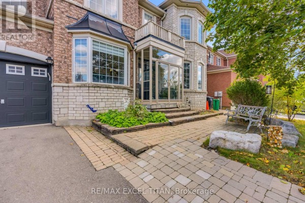 Front entryway of a large house with a paved walkway, stone steps, a bench, and greenery. - 7 Braydon Boulevard, Brampton