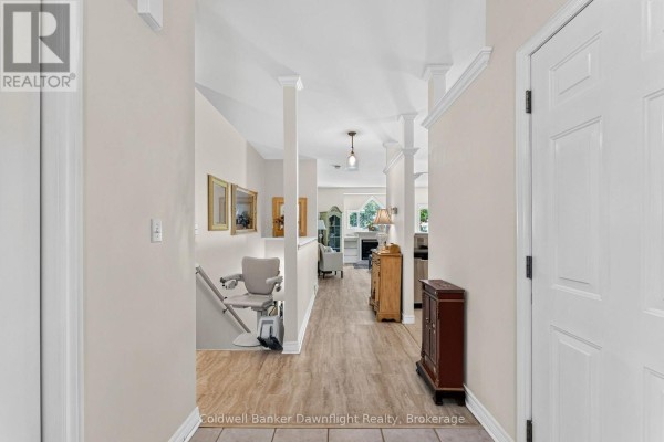 Hallway with light wood flooring, a lift chair, and views into the living area. - 7 Brookside Place, South Huron