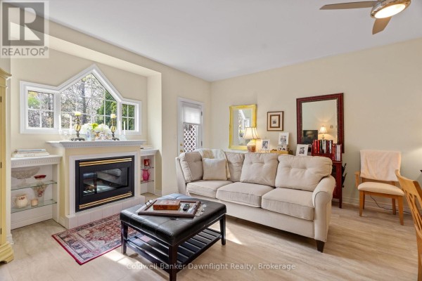 Living room with a sofa, ottoman, fireplace, and a unique bay window. - 7 Brookside Place, South Huron