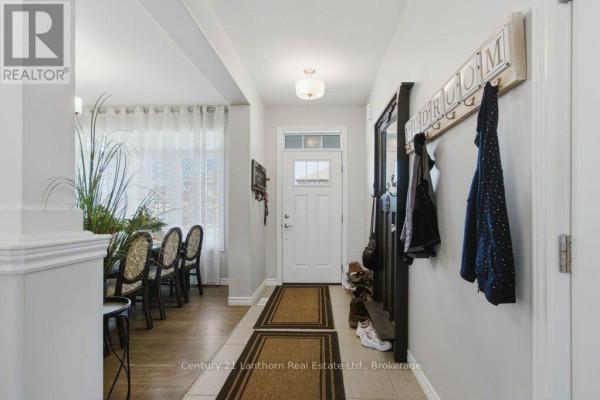 Interior hallway with a white door, coat rack with jackets, mirror, and view into a dining room. - 7 Cottonwood Drive, Belleville