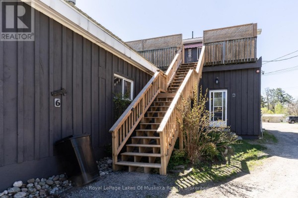 Wooden stairs lead to a second-story entrance on the dark grey wood-sided building. - 7 East Airport Road, Huntsville