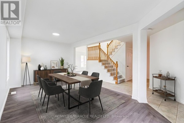 Dining room with a dark wood table, grey chairs, and a staircase in the background. - 7 Empire Drive, Barrie