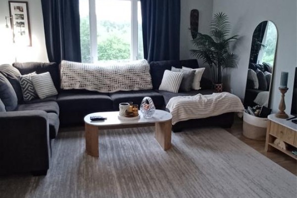 Close-up view of a dark grey sectional sofa with decorative pillows and throws in a living room with dark curtains. - 7 Genge's Road, Glovertown