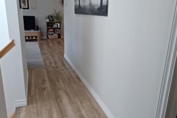 Hallway view with light wood floors, white baseboards, and a large framed nature photograph on the wall. - 7 Genge's Road, Glovertown