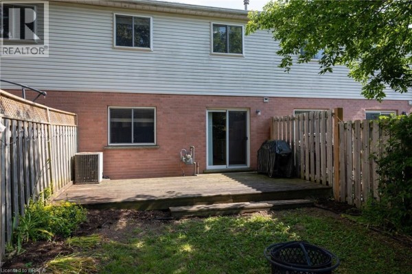 Rear exterior of townhouse with brick lower level, vinyl upper level, and wooden deck. - 7 Graystone Court, Paris