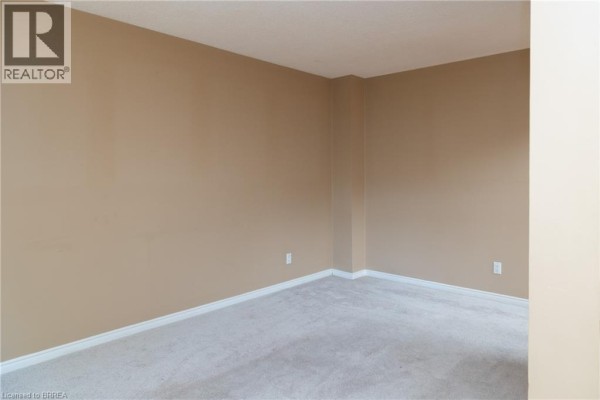 Interior shot of an empty room with beige walls, white trim, and light grey carpet. - 7 Graystone Court, Paris
