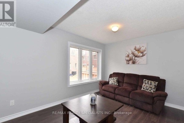 A small living room with a brown sofa, dark coffee table, and a window. - 7 Hobart Gardens, Brampton