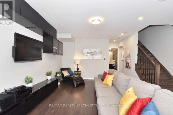 Living room with grey sectional sofa, chaise lounge, mounted TV, and dark wood floors. - 7 Hobart Gardens, Brampton