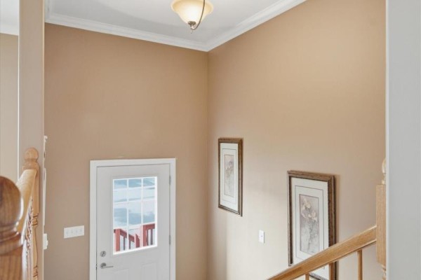 Interior view of a doorway with a glass door and two framed pictures on a beige wall. - 7 Irish Loop Street, St  John S