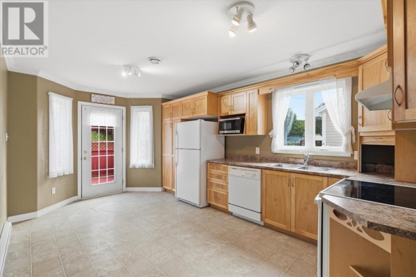 Kitchen with light wood cabinets, white appliances, and a door leading to a red deck. - 7 Irish Loop Street, St  John S