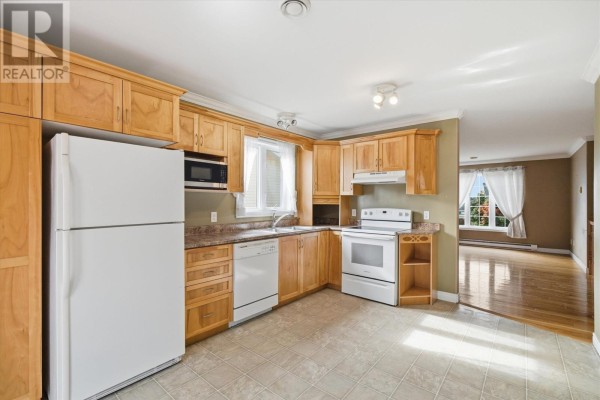 Kitchen with light wood cabinets and white appliances, with an adjacent room visible. - 7 Irish Loop Street, St  John S
