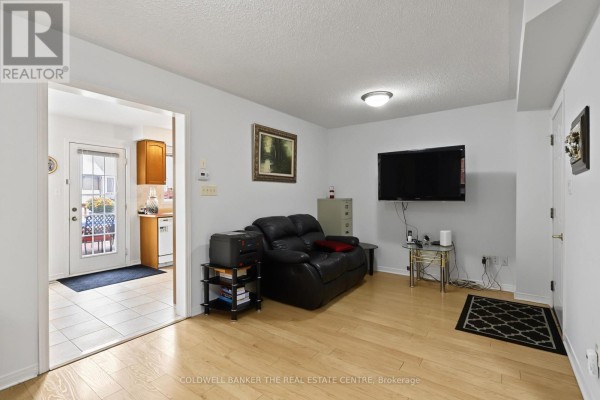 Family room with a black leather sofa, television, and doorway leading to the kitchen. - 7 Isabella Garden Lane, Whitchurch Stouffville
