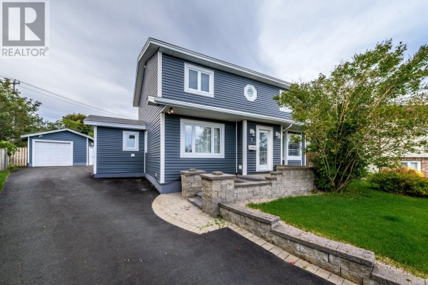 Front exterior of a dark blue two-story house with a detached garage and paved driveway. - 7 Jacobs Place, Mount Pearl
