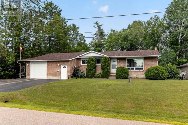 Front view of a brick bungalow with green lawn and mature trees. - 7 Martin Street, Laurentian Hills