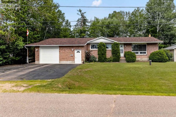 View of the brick bungalow's front exterior, featuring manicured shrubs and a paved driveway. - 7 Martin Street, Laurentian Hills