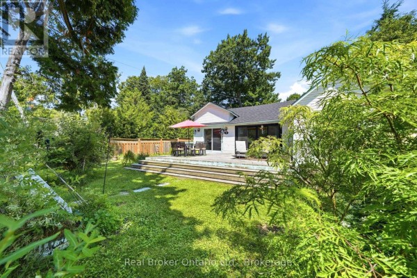 Wooden deck with patio furniture, including a table and chairs under a red umbrella. - 7 Oliver Drive, Tiny