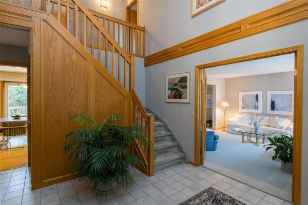 Foyer with a staircase, wood paneling, doorway to a living room, and tiled floor. - 7 Princemere Road, Winnipeg