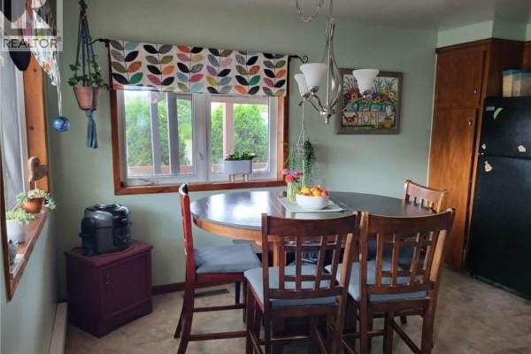 Dining area with a round wooden table, four chairs, and a window overlooking greenery. - 7 Principale Street, Eel River Crossing