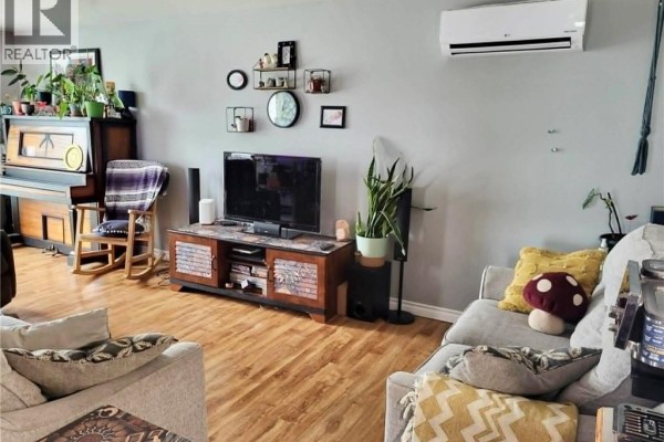 Living room with gray walls, wood laminate flooring, a TV, sofas, and an upright piano. - 7 Principale Street, Eel River Crossing