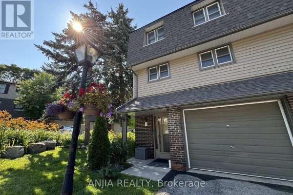 Townhouse exterior with beige siding, dark roof, and attached garage. - 7 Purple Sageway, Toronto