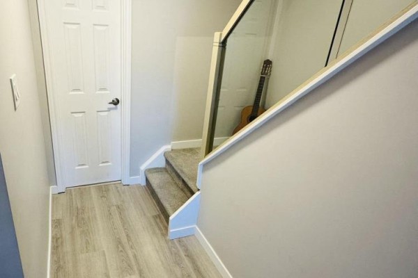 Hallway with light grey walls, light wood-look floor, and carpeted stairs. - 7 Purple Sageway, Toronto