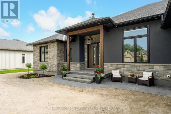 Covered entryway of the house with stone steps, two chairs, and potted plants. - 7 Reynolds Road, Tiny
