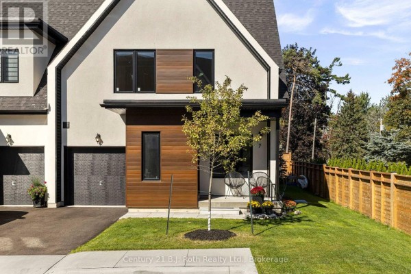 Close-up of the townhouse facade featuring contrasting stucco and horizontal wood siding, black windows, and a covered entryway. - 7 Rice Lane Road, Orillia