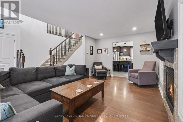 Living room with dark gray sectional sofa, coffee table, stone fireplace, and view of kitchen. - 7 Richer Street S, North Stormont