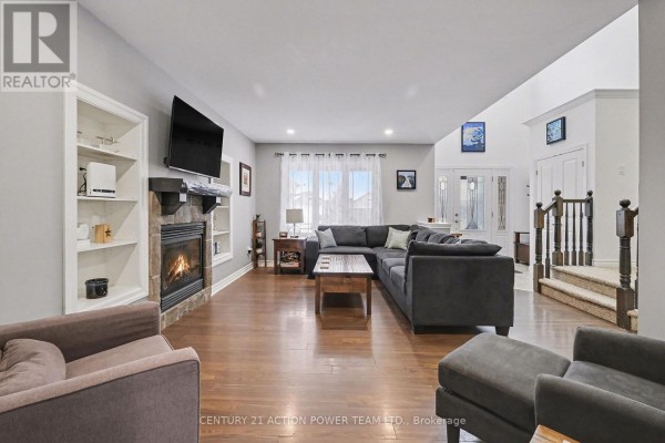 Spacious living room with stone fireplace, built-in shelving, sectional sofa, and hardwood floors. - 7 Richer Street S, North Stormont