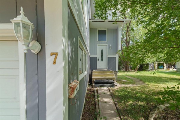 View of the front entrance with a white door and concrete steps leading up, a mailbox attached to the side of the house. - 7 Scotswood Drive, Winnipeg