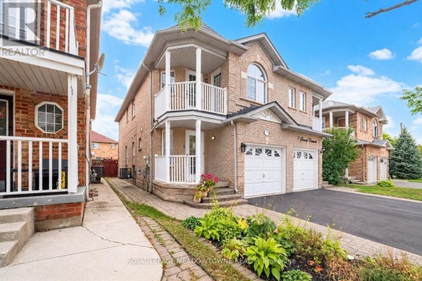 Side view of a brick townhouse showing the entrance and a second-story balcony with white railings. - 7 Secord Crescent, Brampton