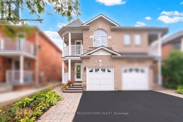 Front view of a detached brick house with a peaked roof, arched window, and double garage. - 7 Secord Crescent, Brampton