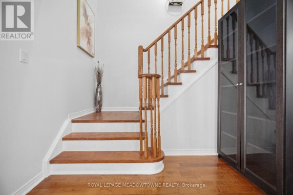 Interior view of a staircase with wooden banister, white risers, and hardwood floors. - 7 Secord Crescent, Brampton