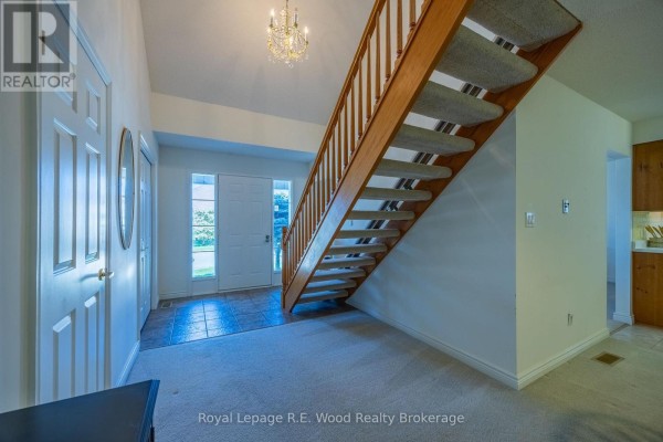 Foyer with a white front door, adjacent to a staircase and a doorway to a kitchen. - 7 Seres Drive, Tillsonburg