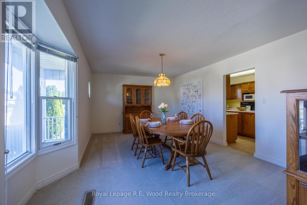 Dining room with a large bay window, a wooden dining set, and a hutch. - 7 Seres Drive, Tillsonburg