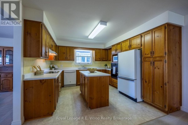 Kitchen with wooden cabinets, island, and white appliances - 7 Seres Drive Tillsonburg