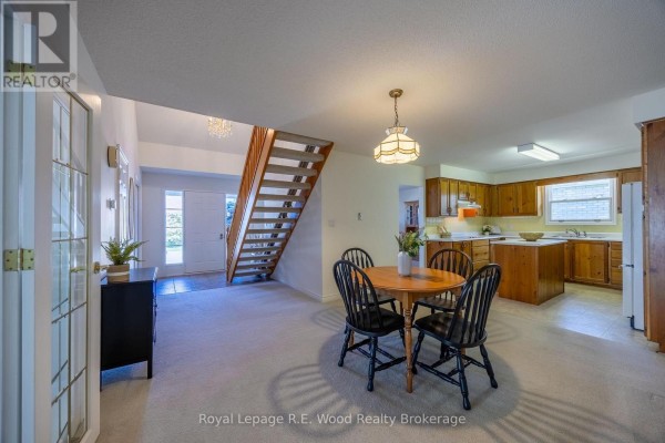 Open concept living, dining, and kitchen area with staircase and chandelier. 7 Seres Drive Tillsonburg