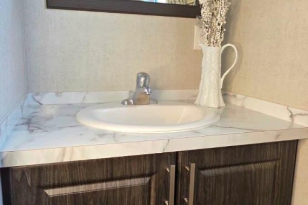 White oval sink with a chrome faucet on a marble-patterned vanity with dark wood cabinets. - 7 Willow - 4449 Milburough Line, Burlington