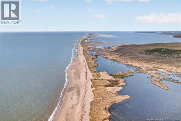 Expansive view of a sandy beach meeting calm water, with marshy land and trees in the background. - 7.1 Acres Chemin De La Cedrière, Riviere Du Portage