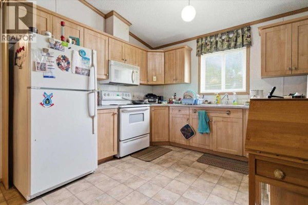 Living room with wood trim, a wood stove, a television, and a coffee table. - 70, 25039 Township Road 722, Rural Grande Prairie No  1, County Of