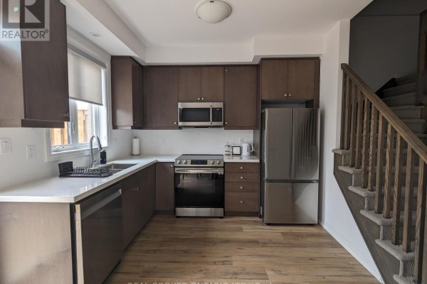 Kitchen with dark wood cabinets, stainless steel appliances, and hardwood floors. - 70 - 461 Blackburn Drive, Brantford