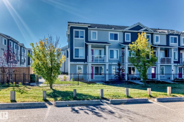 View of multiple townhouses with light blue and dark blue siding, balconies, and green lawns. - #70 16335 84 St Nw, Edmonton